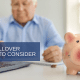 Piggy bank with man in background working on computer words 401(K) Rollover Options to Consider
